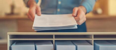 Organizing important documents, homeowner places insurance papers into file photo
