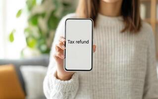 Smiling woman holding smartphone displaying tax refund information, showcasing excitement and relief. Perfect for financial themes photo