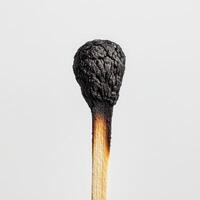 close up of burnt matchstick head, showcasing intricate textures and details. charred surface contrasts with wooden stick photo