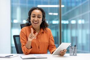 A cheerful professional wearing a headset holds a tablet during a customer support interaction. The setting is contemporary office, emphasizing efficiency and technology in delivering quality service photo