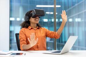 Woman using VR headset at desk, immersed in virtual environment. Professional setting highlights technology's role in innovation, creativity, and productivity in office work. photo