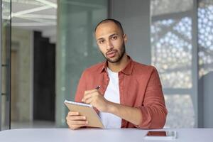Webcam view, serious focused man looking into camera listening to online business meeting and remote conference with colleagues, businessman working in the middle of office at workplace. photo