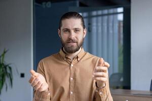 A professional-looking man gestures expressively during a presentation or collaborative meeting in a modern office setting. photo