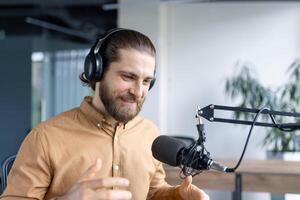 Podcaster speaking into a microphone wearing headphones during a studio recording session. The individual engages in expressive gestures, emphasizing a lively conversation or broadcasting interaction photo