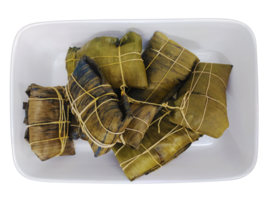 Delicious tamales, meticulously wrapped in banana leaves and tied with twine, rest in a white rectangular dish. A vibrant overhead shot, perfect for food blogs, culinary websites, and recipe books. png