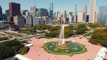 Grand Fountain in Urban Park with City Skyline Background. An expansive view of a grand fountain in a public urban park, featuring intricate sculptures and water jets, with a backdrop of towering video