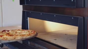 Hot delicious pizza. Pizzeria master takes out ready pizza from the oven. Chef is pulling out fresh pizza with a special pizza spatula in the kitchen. video