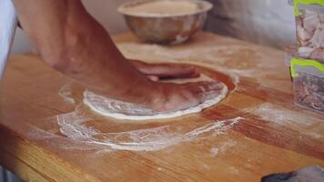 Baker kneading dough in flour on table. Hands of professional bakery chef on dough. Man forming dough of a round form for pizza. video