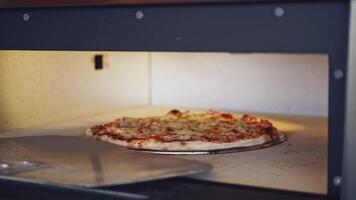 Pizza is getting ready in oven. Chef opening oven door and checking pizza readiness. Cook checks pizza for readiness using the pizza ring. video