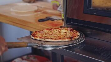 Pizza is ready. Pizzeria master making pizza. Chef pulling pizza out of the oven using the pizza spatula. Cook puts the finished pizza on the plate. Tasty pizza. video