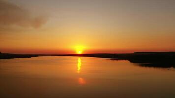 Amazing sunset over the water. Orange background from the setting sun. Golden path reflects on river in the evening. video