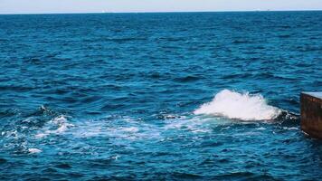 Amazing water background. Waves swaying on the sea water. Beautiful blue water waves with white foam crashing on the dock. Slow motion. video