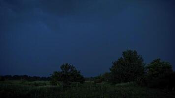 Lightning strikes on the dark sky. Stormy sky with lightning flashing over green nature in the evening. Dark blue sky becomes light with a lightning splash in summer. video
