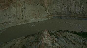 Drone Flying Over Mountain Path Alongside River in Rocky Valley video