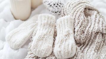 Cozy winter scene with cream-colored knitted mittens, sweater, and snow. photo