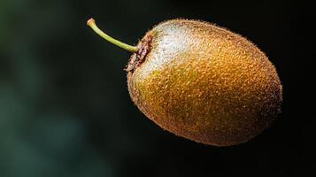 Ripe golden kiwi fruit with stem, isolated on black background. photo