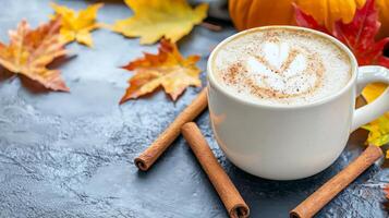 Autumnal latte art in white mug with cinnamon sticks and fall leaves. photo