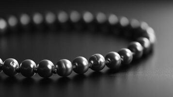 Close-up of a dark grey pearl necklace on a black surface. photo