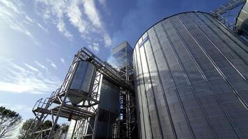 Grain elevators for drying seeds. Modern grain terminal. White smoke goes into the air from grain-drying complex. Metal tanks of elevator outdoors. video