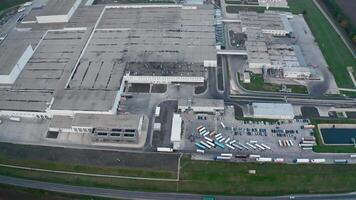 Large industrial complex. Exterior of production plant on field. Grey manufacturing with car parking. Motion camera to the left. Aerial view. video