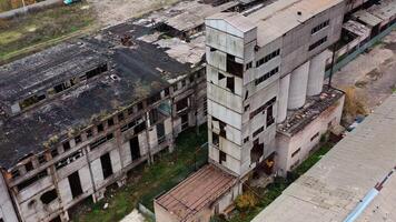 Ruined factory with damaged roof. Abandoned buildings on the field of military actions. Destroyed architecture. Aerial view. video
