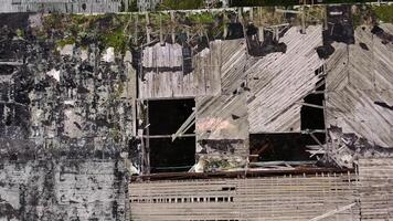 Damaged roof of a building during military action. Abandoned building with many holes outdoors. Top aerial view. Camera rising up. video