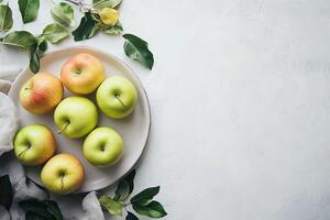 Fresh apples on a white plate with leaves photo
