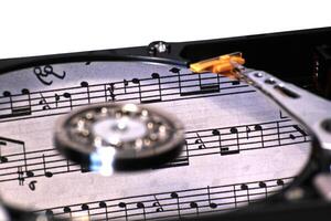 Hard disk on a white background with reflection of music notes. photo