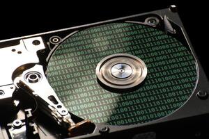 Hard disk on a black background with reflections on ones and zeros binary code. photo