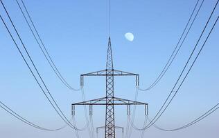 Symmetrical view on a high voltage power line The moon is visible in the background photo