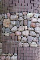 Wall with differently shaped stones in metal mesh photo