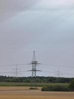 Three pillars of high voltage power lines in Mecklenburg-Vorpommern, Germany. Sunbeams are visible on the cloudy sky. photo