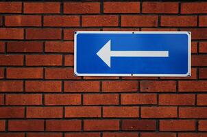 Arrow sign on a red brick wall. photo