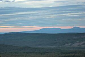 Different shades of blue and orange over forest landscape seen from a Swedish mountain. photo