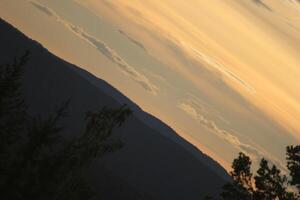 Sky with different shades of orange over a mountain silhouette in Sweden in unusual angle. photo
