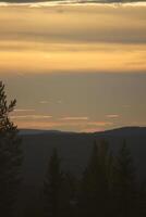 Sky with different shades of orange over a mountain silhouette in Sweden photo