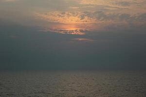 Orange sunbehind clouds over the open sea. photo