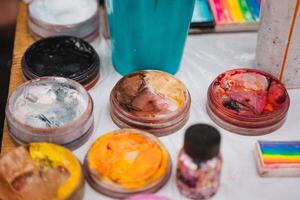 A sturdy table topped with an assortment of vibrant and colorful face paints, perfect for creative expression and artistic endeavors during fun events or lively celebrations photo