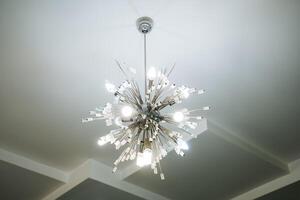 A stunning and beautifully designed chandelier gracefully hangs from the ceiling, adding an exquisite charm and a warm ambiance to the entire room, enhancing its overall aesthetic appeal photo