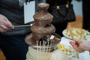 Indulge in a delightful experience with a mouthwatering chocolate fountain at a festive gathering, complemented by an assortment of dippers and skewers for everyone to enjoy photo