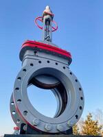 This image features a detailed closeup of a valve, with a beautiful blue sky serving as the backdrop, creating a striking contrast against the metallic structure of the valve photo