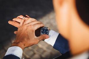 A sharply dressed man in a meticulously tailored suit checks his elegant watch to ensure he is on time for a crucial meeting that could significantly affect the trajectory of his career photo