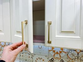 A person is carefully opening a cabinet door in a kitchen area, likely to retrieve or store something essential, while the overall environment is designed for functional use and comfort photo