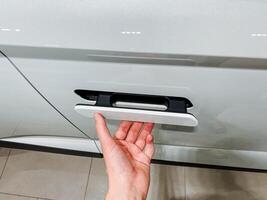 A person is using their hand to open the door of a car, demonstrating a simple yet significant action that showcases the interaction with automotive design and functionality photo