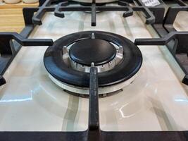 This is a closeup image of a modern gas cooktop burner, showcasing a detailed control knob along with strong metal grates, all set within an elegantly designed kitchen space photo