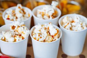 Experience the delightful taste of deliciously buttery popcorn, expertly served in cheerful, fun white cups, making it the perfect snack for your unforgettable movie night photo