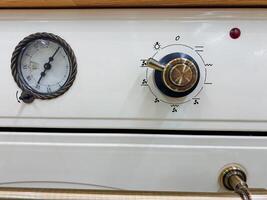 A classic white stove featuring a gauge for monitoring and a knob for controlling the temperature, making it a functional and essential home appliance for cooking and baking photo