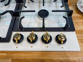 A classic gas stove that features four burners is currently placed on a sturdy wooden counter, highlighting its functionality and the beauty of natural wood in the kitchen environment photo