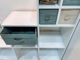 A white shelf with a drawer in the middle of it photo