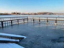 A picturesque and frozen lake is beautifully captured in this stunning image, with a rustic dock gracefully positioned in the background, creating an incredibly serene winter scene photo